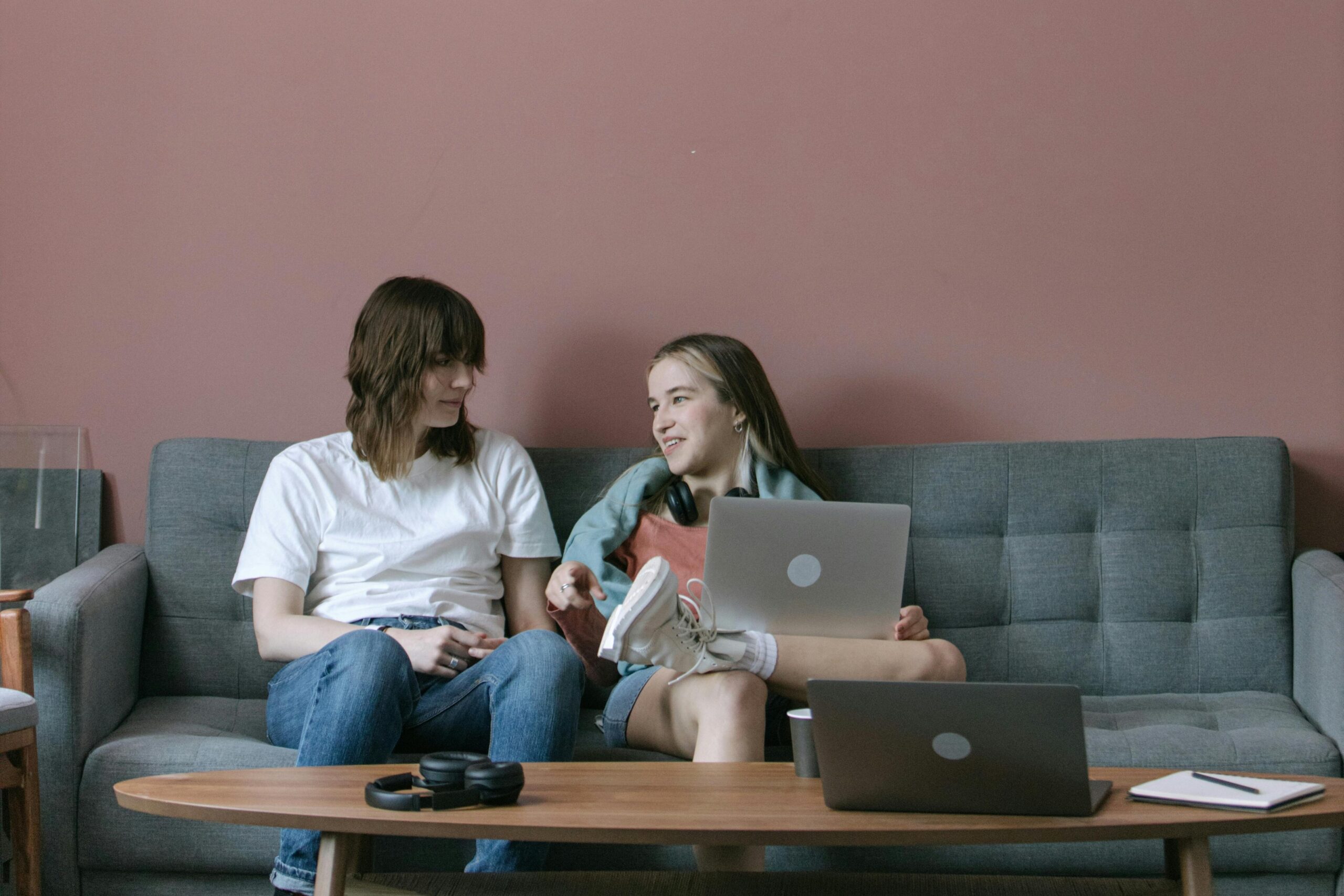 A diverse group of young adults collaborating casually on a sofa with laptops.